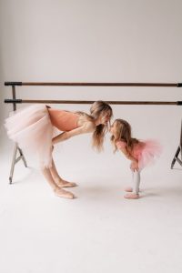 A heartwarming scene of a mother and daughter practicing ballet in a studio, sharing a kiss.