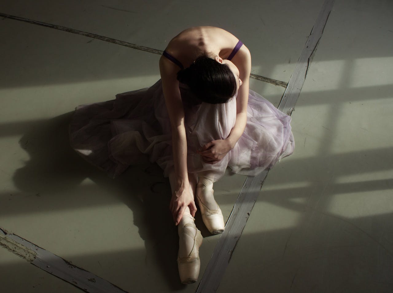 Elegant ballerina in delicate light, resting after a practice session.